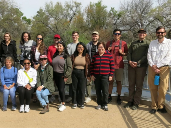 sharon megdal with students on field trip. trees behind them