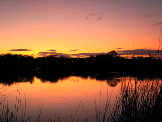 Jimmy Tonthat photo of lake at sunset. Rich reds and yellows and silhouetted hills 