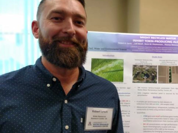 a man with brown hair in front of a presentation board