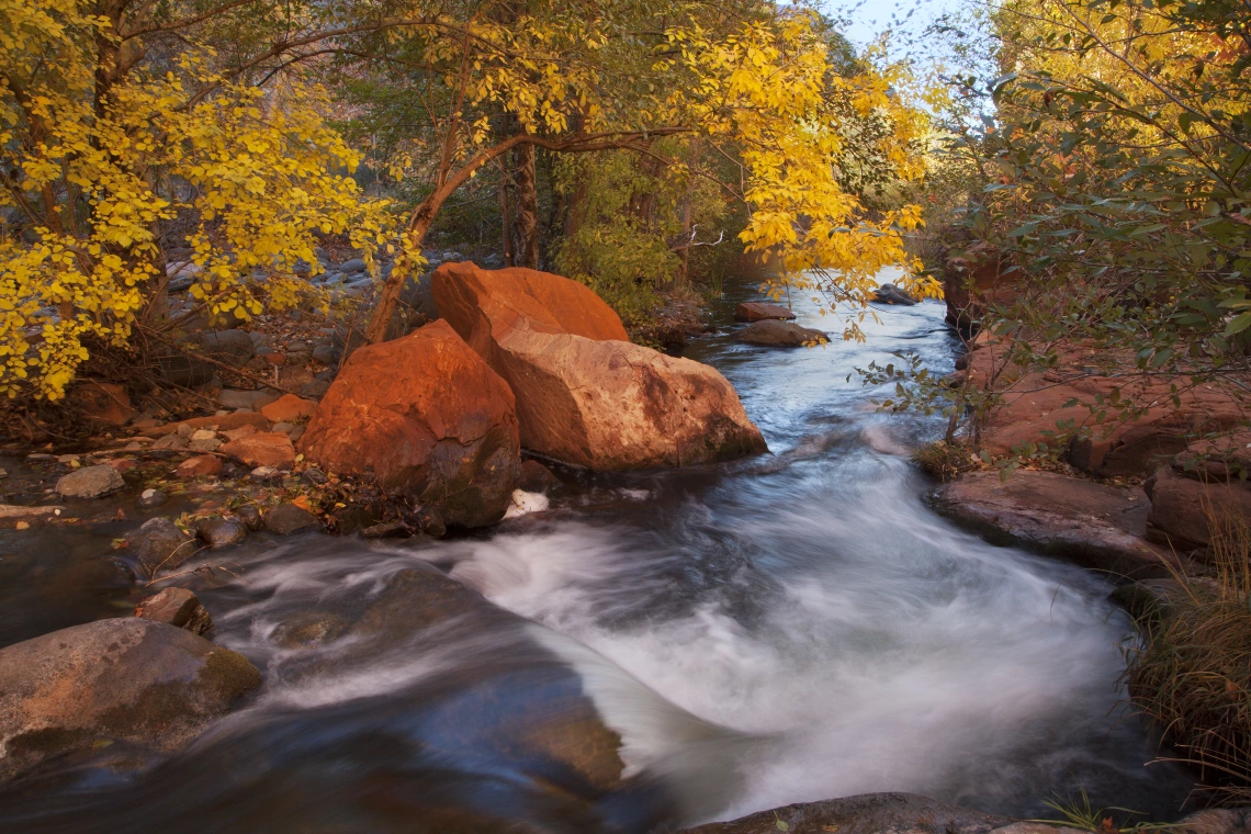 Dave Wilson photo showing West Clear Creek in autumn. Red rocks and leaves with fall colors can be seen