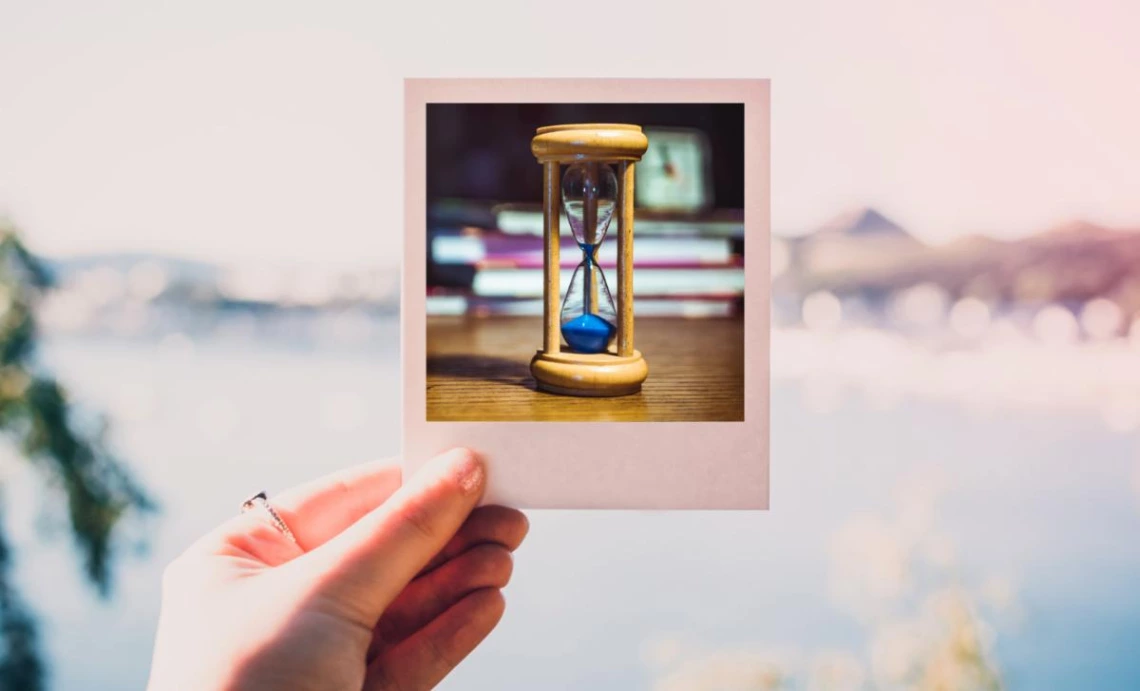 a hand holding up a Polaroid with an hourglass